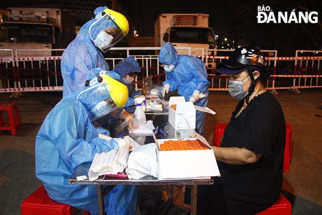 A medical worker was collecting personal information from a trader before getting a test. Photo: XUAN DUNG