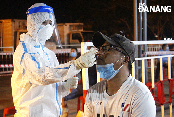 A medical worker took a throat and nasal swab of a trader. Photo:  XUAN DUNG