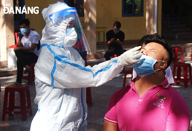 A medical staff took a combined throat and nose swab of a worker in food services in Ngo May Primary School located in Phuoc My Ward in the morning of May 16. Photo: XUAN DUNG