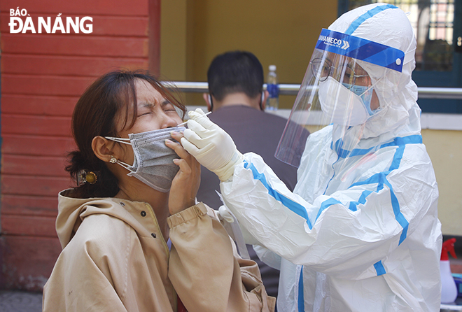 A medical staff took a combined throat and nose swab of a worker in accommodation services in Pham Ngoc Thanh Junior High School in Nai Hien Dong Ward in the morning of May 16. Photo: XUAN DUNG