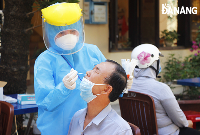 Nhân viên y tế quận Hải Châu lấy mẫu xét nghiệm virus SARS-CoV-2 cho đại diện 1 hộ gia đình tại phường Nam Dương (quận Hải Châu) sáng 18-5. Ảnh: XUÂN DŨNG