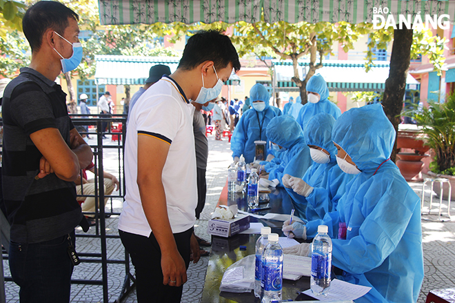 Người dân phường Nại Hiên Đông xếp hàng khai báo thông tin trước khi lấy mẫu xét nghiệm SARS-CoV-2. Ảnh: XUÂN DŨNG