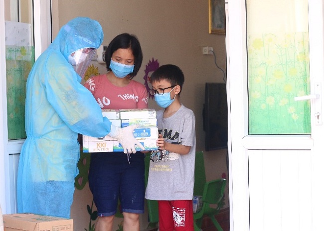 Người dân, trẻ em trong nơi cách ly tập trung tại huyện Thuận Thành, một trong những điểm nóng về dịch ở Bắc Ninh, đón nhận món quà từ Vinamilk.