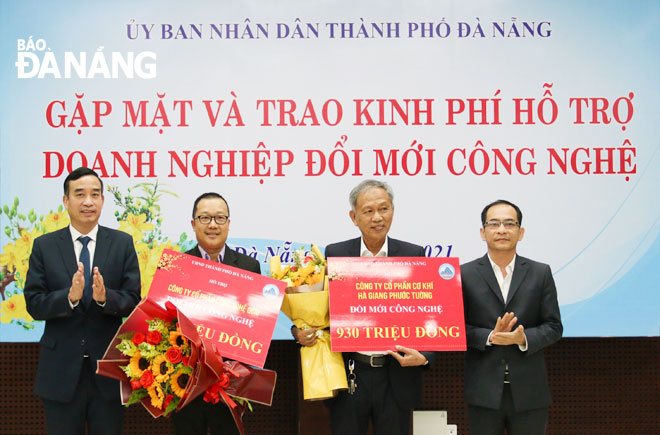 Chủ tịch UBND thành phố Lê Trung Chinh (bìa trái) trao kinh phí hỗ trợ doanh nghiệp đổi mới công nghệ tháng 2-2021. Ảnh: P.V