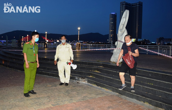 Lực lượng chức năng phường Hải Châu 1 (quận Hải Châu) nhắc nhở một người dân không tập thể dục nơi công cộng và đeo khẩu trang đúng cách. Ảnh: HOÀNG HIỆP