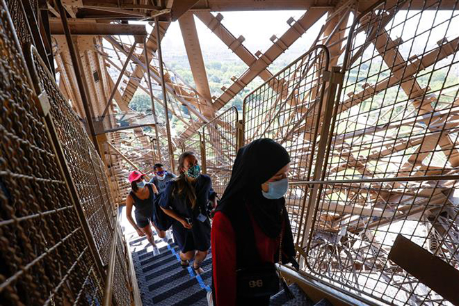 Du khách đeo khẩu trang phòng dịch Covid-19 khi tham quan Tháp Eiffel tại Paris, Pháp. Ảnh: AFP/ TTXVN