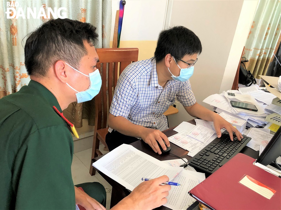  Mr. Ho Nguyen Hai Long (right), a public servant from the My An Ward People's Committee in Ngu Hanh Son District briefs information on voters for to the representative of an election team in the ward.