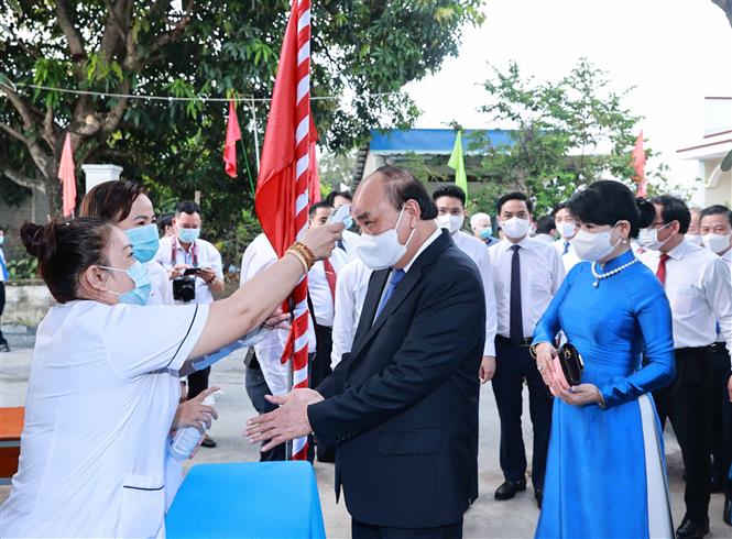 Chủ tịch nước Nguyễn Xuân Phúc rửa tay sát khuẩn và được đo kiểm tra thân nhiệt tại khu vực bỏ phiếu số 041, đơn vị bầu cử số 10 thuộc thị trấn Củ Chi. Ảnh: Thống Nhất/TTXVN