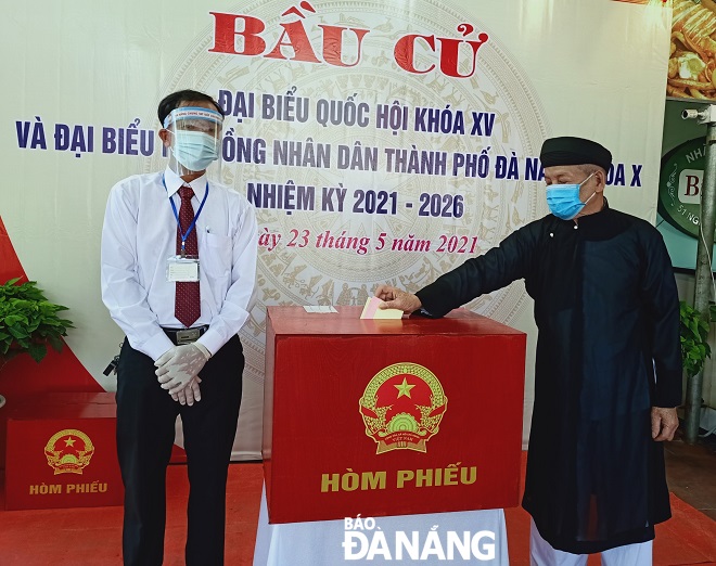 An older man in traditional dress casts ballot in polling station No. 3 in Man Thai Ward, Son Tra District. PHOTO: DUC LAM