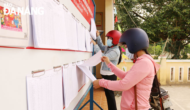 Người dân xã Hòa Tiến (huyện Hòa Vang) quan tâm tìm hiểu tiểu sử và chương trình hành động của các ứng cử viên. (Ảnh chụp trước ngày 23-5)					          Ảnh: THANH TÌNH