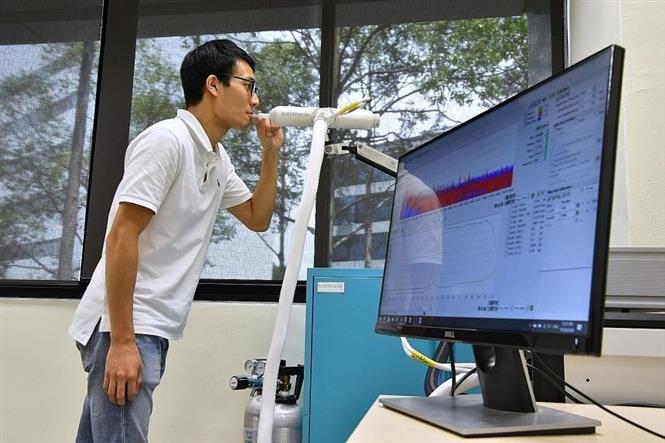 Nhân viên minh họa hình thức xét nghiệm Covid-19 qua hơi thở tại một phòng thí nghiệm ở Singapore ngày 29-10-2020. Ảnh: REUTERS/TTXVN