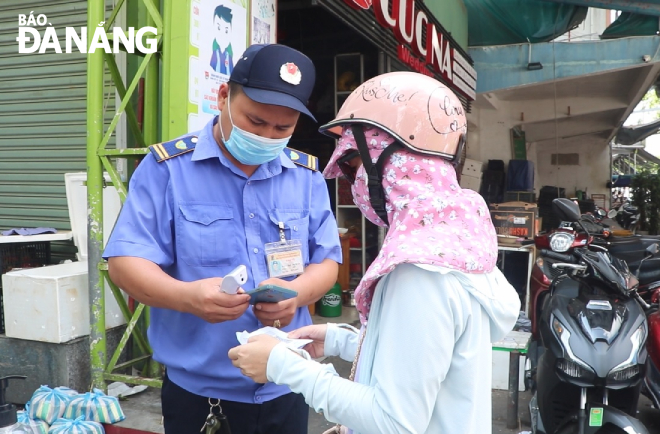 A woman shows her QR Code entry card to a guard at Con Market on Tuesday morning. Photo: VAN HOANG