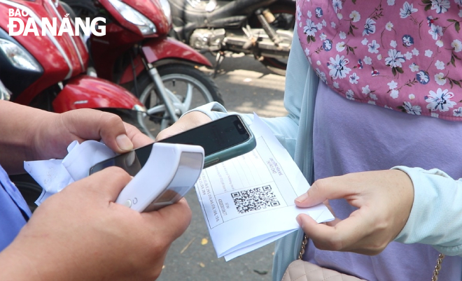  On arrival at the market, people show their QR Code entry cards to guards to scan for confirmation. Photo: VAN HOANG