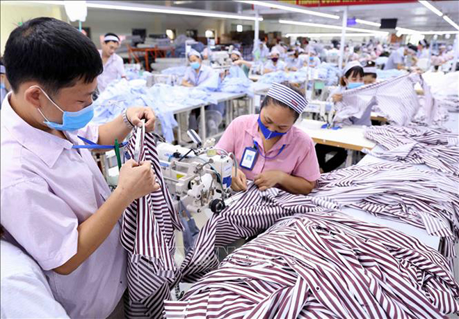 Gia công sản phẩm quần áo bảo hộ lao động và áo sơ mi xuất khẩu sang thị trường Hàn Quốc tại Công ty TNHH KH Vina (Thanh Hóa). Ảnh minh họa: Vũ Sinh/TTXVN