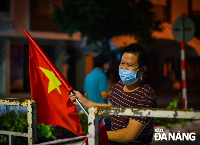  Some residents waive national flags to celebrate the end of the quarantine period on May 27, 2021. Photo: XUAN SON