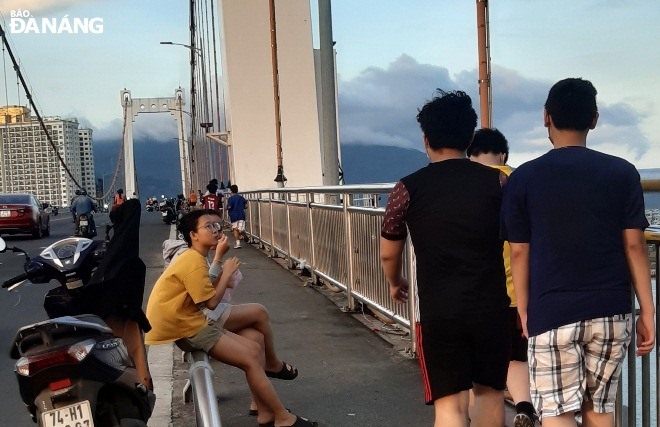 Khổng những không đeo khẩu trang, nhiều trường hợp còn tụ tập trên cầu Thuận Phước để ăn uống và nói cười. Ảnh: LÊ HÙNG