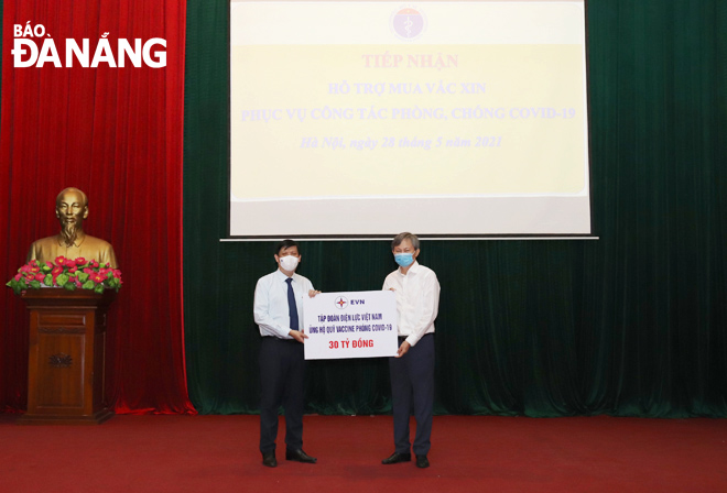 EVN General Director Tran Dinh Nhan presents a symbolic board of donations for COVID-19 vaccine fund to a representative of the Ministry of Health