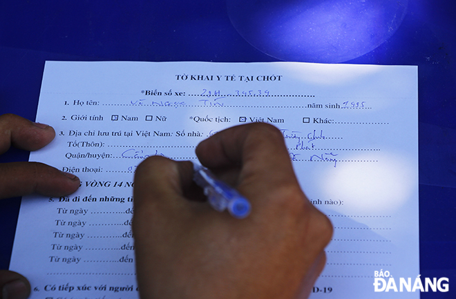  A traveler fills out a health declaration form. Photo: XUAN DUNG