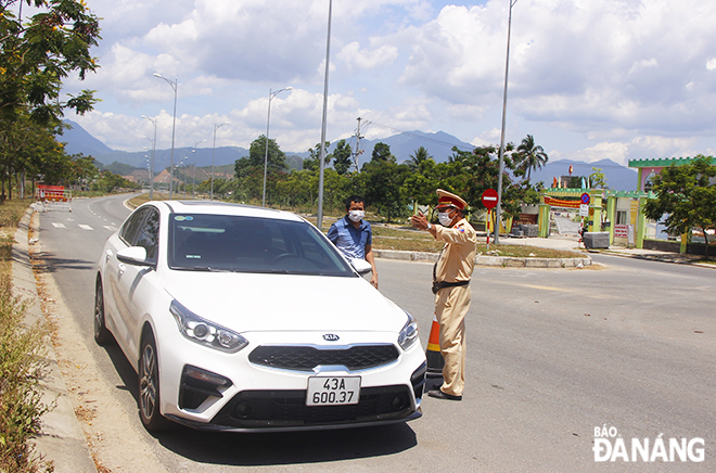  Healthcare workers, police officers, border guards, and volunteer students are staffing the checkpoints around the clock on a daily basis. A car is pulled over for inspection at a checkpoint on the extended Nguyen Tat Thanh