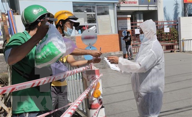 A medical worker at a hospital in Tan Phu district, HCM City receives necessities for patients when the hospital is locked down (Photo: VNA)