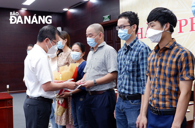 Da Nang Party Committee Secretary Nguyen Van Quang (in white shirt, left) presents gifts and give spiritual encouragement to the medical workers of Da Nang General Hospital who will be sent to the worst-hit locality to tackle Covid-19. Photo: PHAN CHUNG