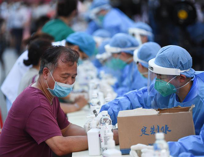 Nhân viên y tế lấy mẫu xét nghiệm Covid-19 cho người dân tại tỉnh Quảng Đông,Trung Quốc. Ảnh: THX/TTXVN