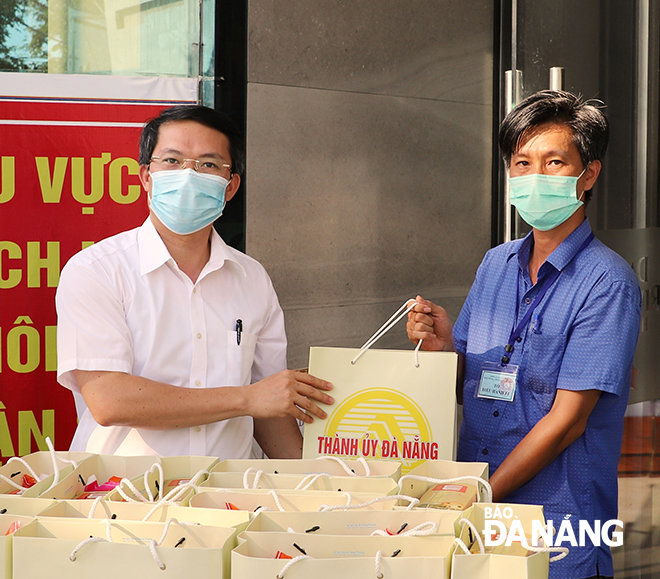 Chief of Office of the municipal Party Committee Nguyen Van Hung hands gifts to the task force staffing at a designated site in Son Tra District to transfer them to children who are being placed under quarantine  due to links with infected patients . Photo: NGOC PHUC