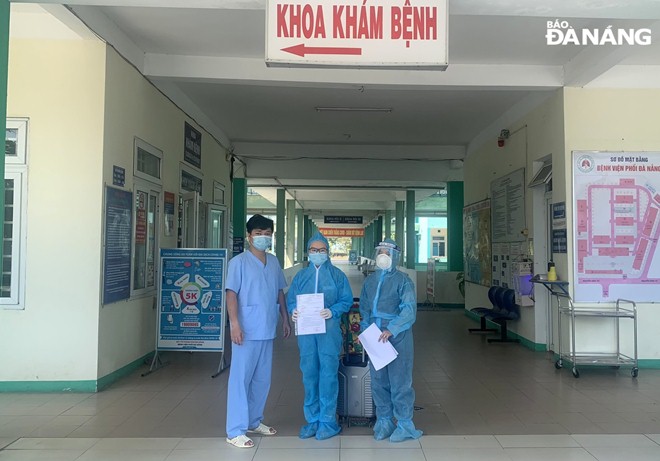 The representative of the Da Nang Lung Hospital hands over discharge papers to the completed-cured patient (centre). Photo: L.HUNG