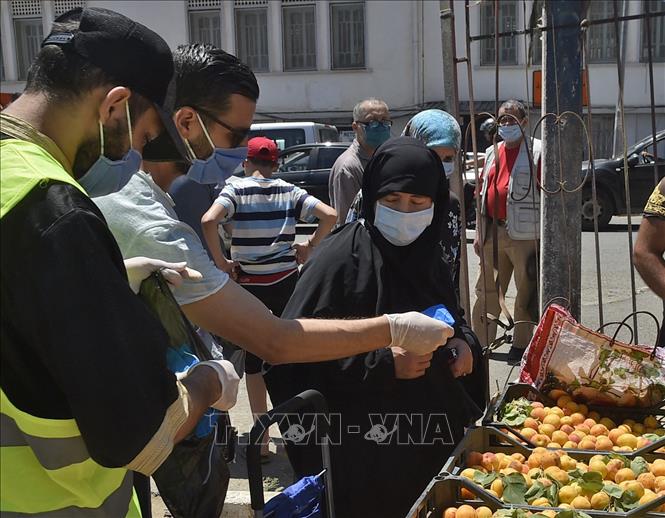 Tình nguyện viên phát khẩu trang phòng dịch COVID-19 cho người dân tại Algiers, Algeria. Ảnh: AFP/TTXVN