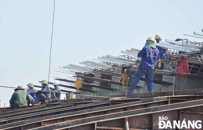 Trong thời tiết nắng nóng, công nhân trang bị thêm nhiều đồ bảo hộ lao động như găng tay, khăn trùm... Trong ảnh: Công nhân thi công dự án đường và cầu qua sông Cổ Cò.  Ảnh: THÀNH LÂN	