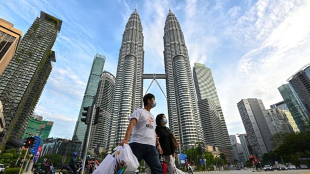 People wearing face masks walk in front of the Petronas Twin Towers in Kuala Lumpur, Malaysia. (Photo: Xinhua)