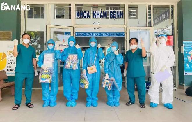 4 bệnh nhân mặc đồ bảo hộ (giữa) nhận giấy xuất viện của lãnh đạo Trung tâm Y tế huyện Hòa Vang. Ảnh: L.H