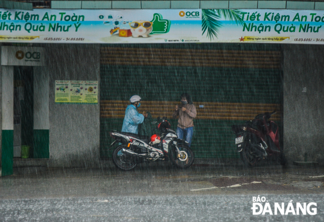 Many road users take shelter from the rain under roadside eaves.