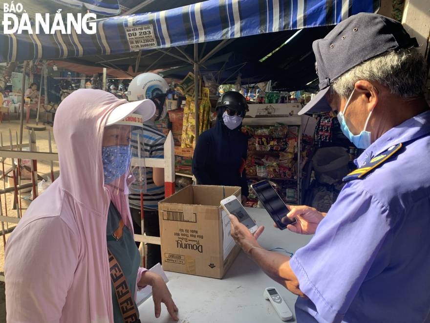 On arrival at the market, people show their QR codes of entry cards to guards to scan for confirmation. Picture is taken at Hoa Cuong wholesale Photo: QUYNH TRANG