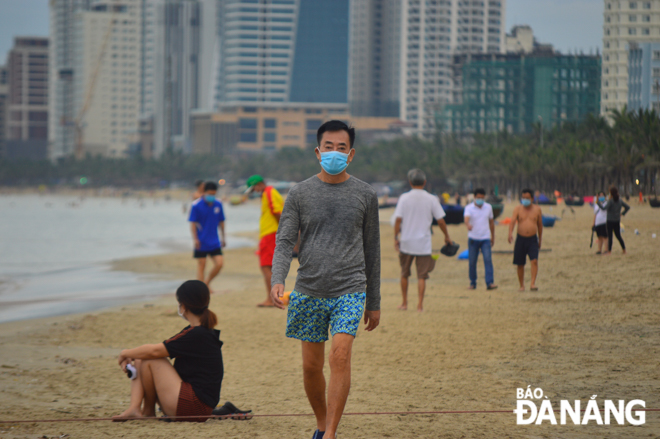 Beach-goers strictly obey the regulations of keeping at least 1m from others, wearing face masks before and after swimming.