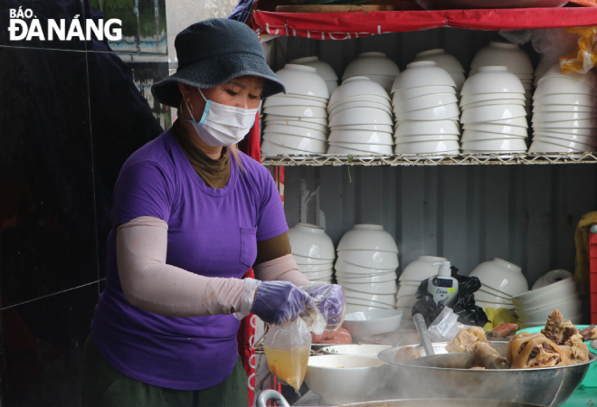 A staff member of a noodle shop Le located on Le Van Thu Street, Son Tra District are seen wearing a face mask and using gloves while selling food. Photo: VAN HOANG