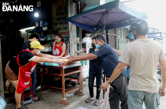 Staff and their customers are seen maintaining a safe physical distance between them at a bread shop on Nguyen Cong Tru Street, Phuoc My Ward, Son Tra District  Photo: VAN HOANG