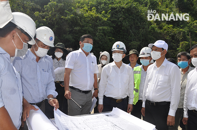 Bí thư Thành ủy Nguyễn Văn Quảng (áo trắng hàng đầu thứ 4 từ phải sang) nghe lãnh đạo Ban Quản lý Nha máy nước Hòa Liên báo cáo tiến độ thi công đập tràn. Ảnh: THÀNH LÂN