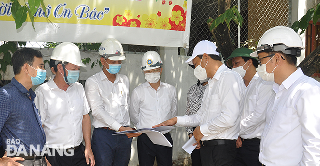 Bí thư Thành ủy Nguyễn Văn Quảng (áo trắng thứ 4 hàng đầu từ trái sang) nghe các đơn vị báo cáo dự án nâng đường dẫn 2 đầu cầu Trường Định . Ảnh: THÀNH LÂN