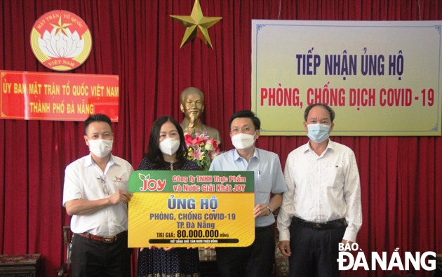 A leader of the Da Nang Newspaper (2nd, left) receives a symbolic board of donations from representatives of JOY Food and Beverage Company on Thursday afternoon. Photo: DAC MANH