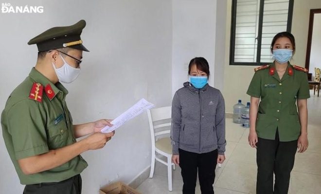 A police officer read a court decision to prosecute Le Thi Kim Anh (middle) after she has been charged with facilitating illegal immigration. Photo: L.H