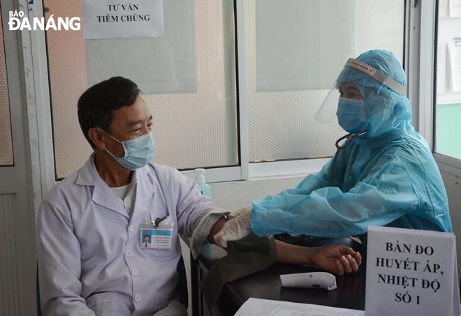 The persons will be asked to have their health checked before before getting vaccinated. In the photo: A medical worker measures the blood pressure of a person before he receives the COVID-19 vaccine. Photo: L.HUNG
