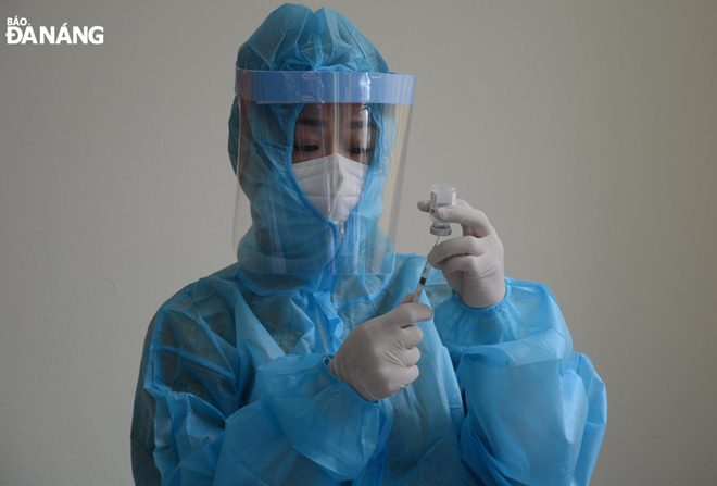 A healthcare worker prepares a vaccine for the person receiving it. Photo: L.HUNG