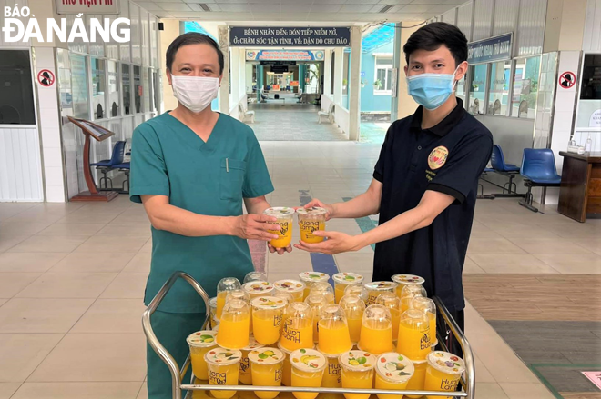 Bác sĩ Nguyễn Đại Vĩnh, Giám đốc Trung tâm Y tế huyện Hòa Vang (trái) vui mừng tiếp nhận những ly nước tiếp sức tuyến đầu từ CLB Hương Lam. Ảnh: NVCC