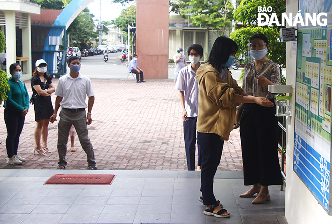 Các thí sinh tại điểm thi Trường THPT chuyên Lê Quý Đôn (quận Sơn Trà) rửa tay sát khuẩn, đo thân nhiệt trước khi vào lấy mẫu xét nghiệm SARS-CoV-2. Ảnh: XUÂN DŨNG
