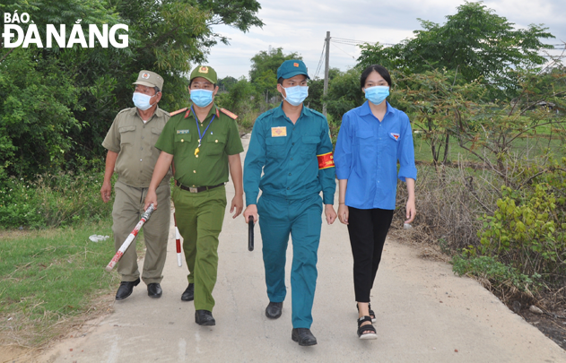 Police, militia, guards and youth union members in  Hoa Quy Ward, Ngu Hanh Son District work together to conduct patrols on trails connecting the city with  Dien Ngoc Ward, Dien Ban Town, Quang Nam Province in a bid to detect arrivals who fail to declare their health  status. Picture was taken on the afternoon of June 11. Photo: LE HUNG