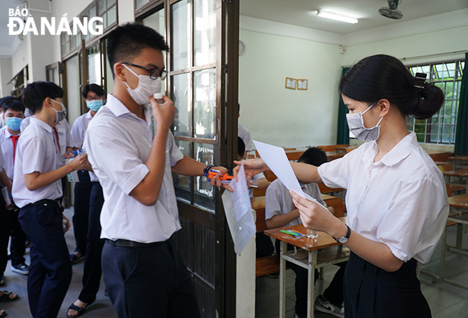 Cán bộ coi thi  điểm danh thí sinh trước khi vào phòng thi tại điểm thi Trường THPT Phan Châu Trinh (quận Hải Châu). Ảnh: XUÂN DŨNG