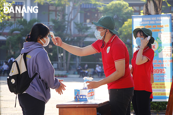 Youth Union members staffing at the entrance gate of the Hoang Hoa Tham High School in Son Tra District to check body temperature of test takers and disinfect their hands on Tuesday morning. Photo: XUAN DUNG