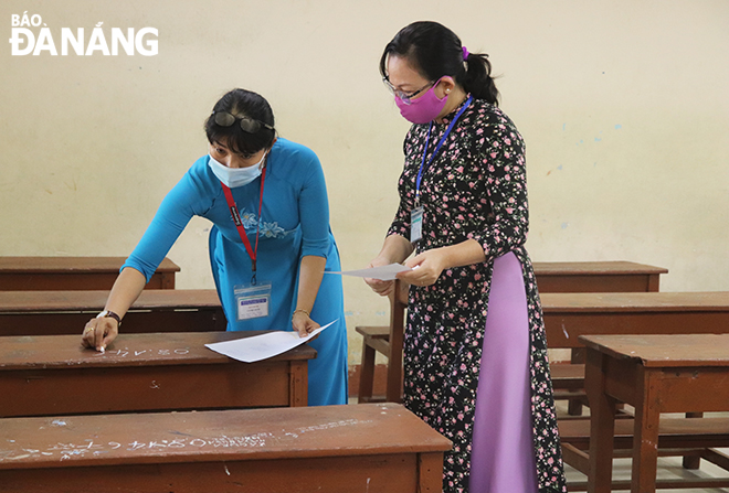 Examination invigilators write codes of test takers’tables at exam hall. Photo: NGOC HA