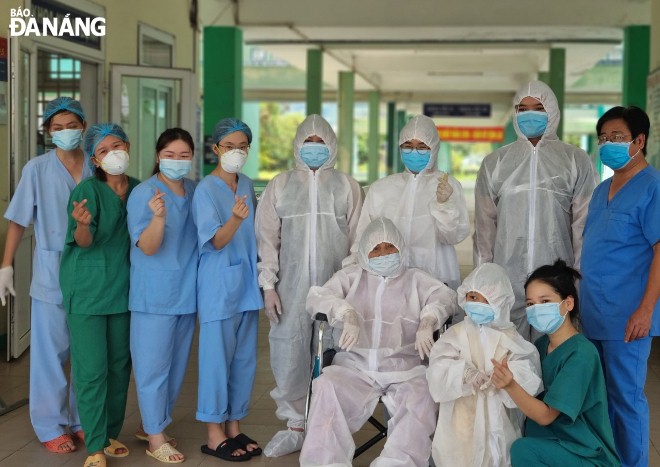 Staff of the Da Nang Lung Hospital and the recovered patients (in white protective clothing) pose for a photograph before they leave the hospital on Tuesday morning. Photo: L.HUNG